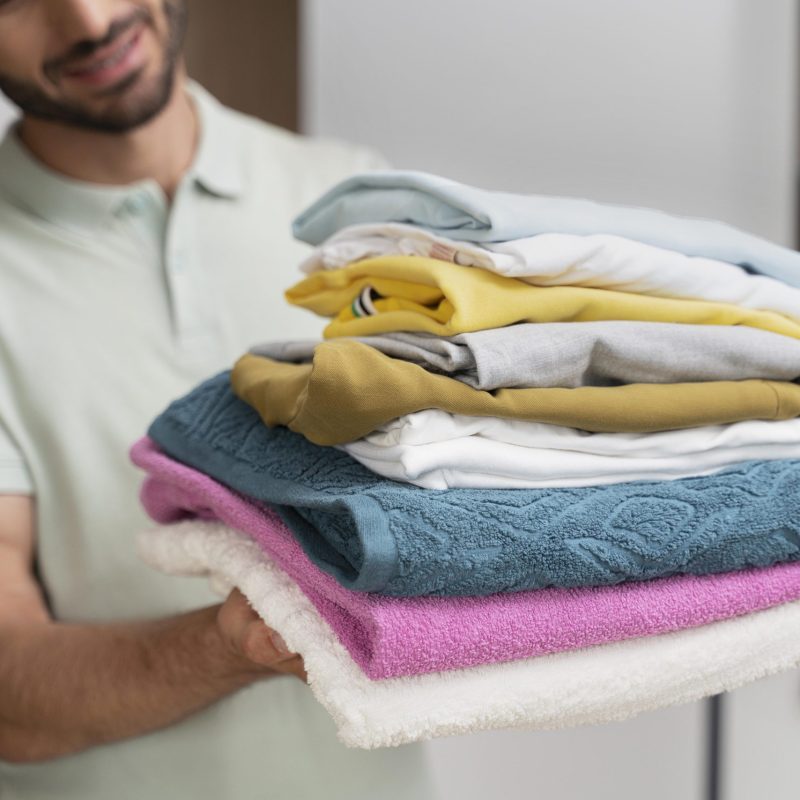man-holding-pile-clean-clothes